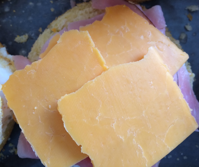 Photo of a glutino gluten free english muffin with cheddar cheese on top. 